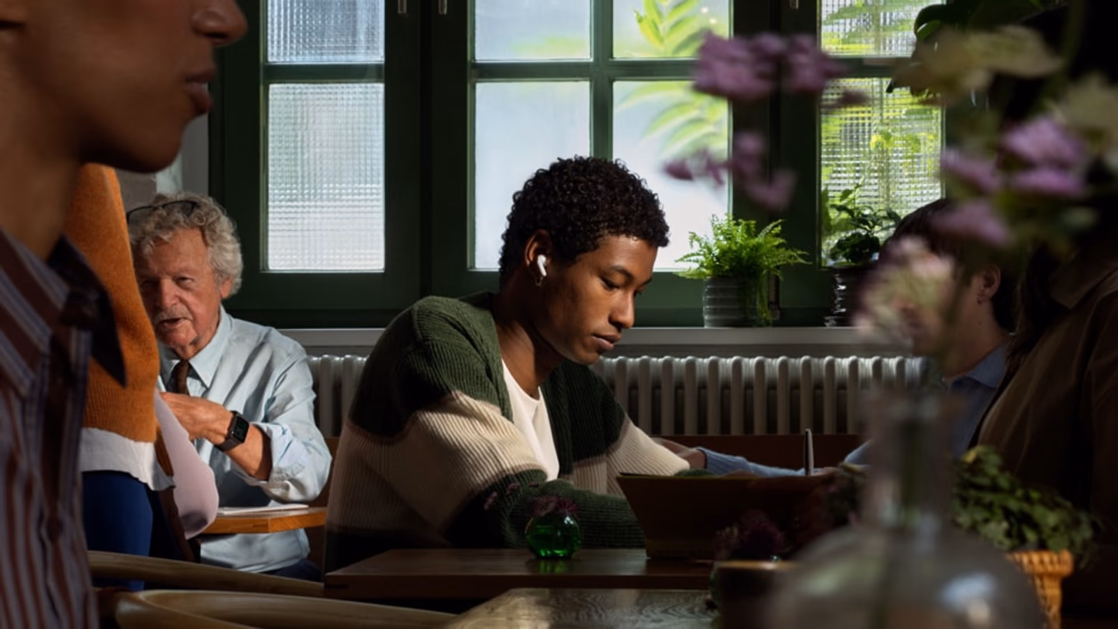 The actual AirPods 5 design shown in Apple's lifestyle photography.